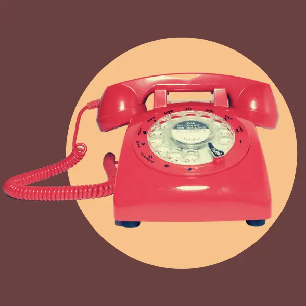 Un telefono rojo sobre un círculo amarillo. El fondo es marrón 